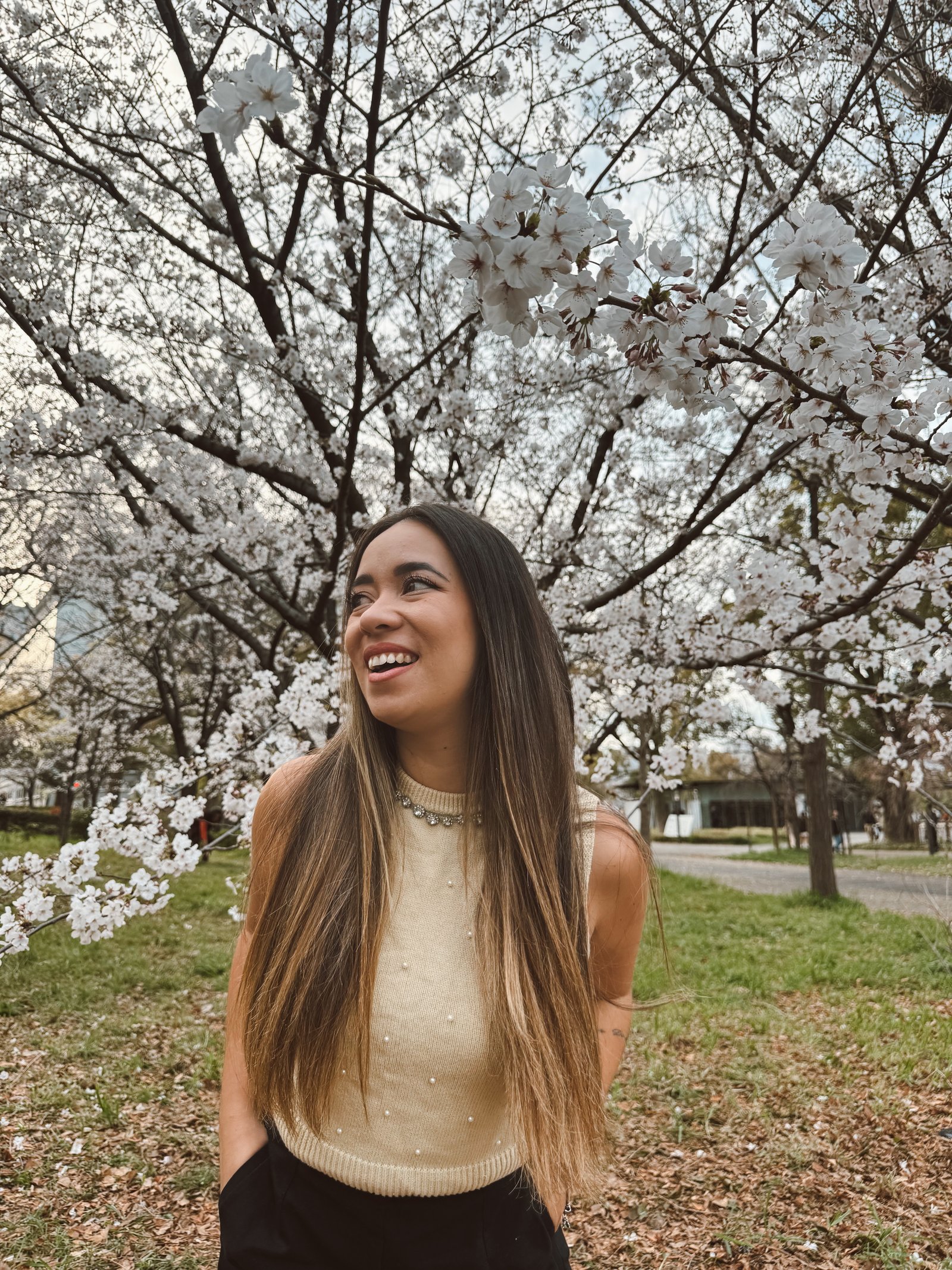 Denise sorrindo sob as cerejeiras em flor