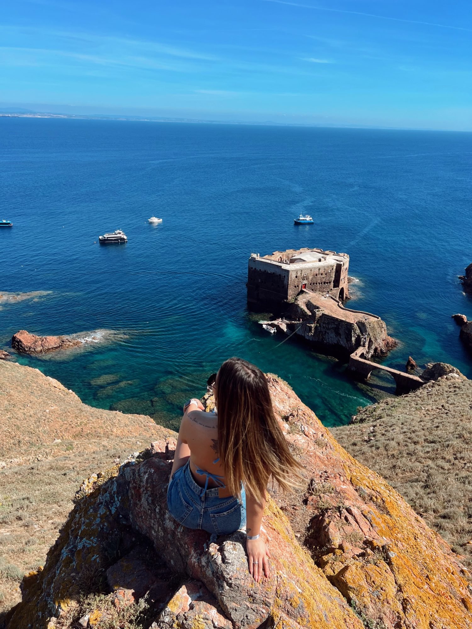 Denise sentada num penhasco sobre o forte das Berlengas, em Portugal