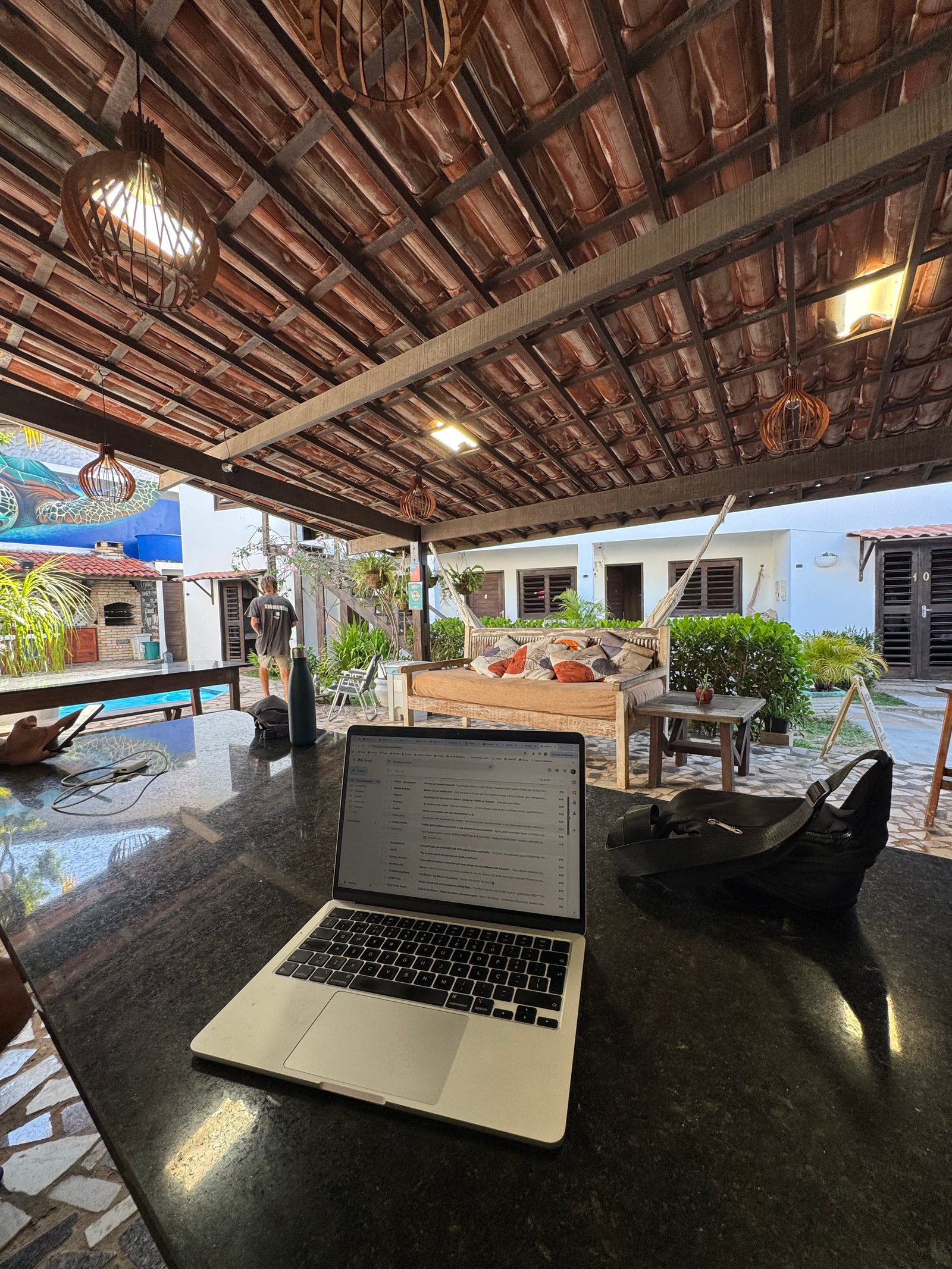 Laptop aberto numa varanda tropical, trabalho remoto à beira-mar